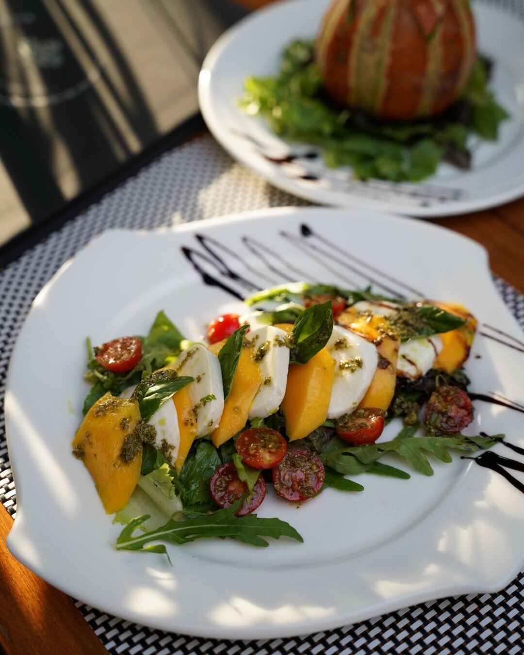 Mozzarella, mango and cherry tomatoes on rocket, plated on white china