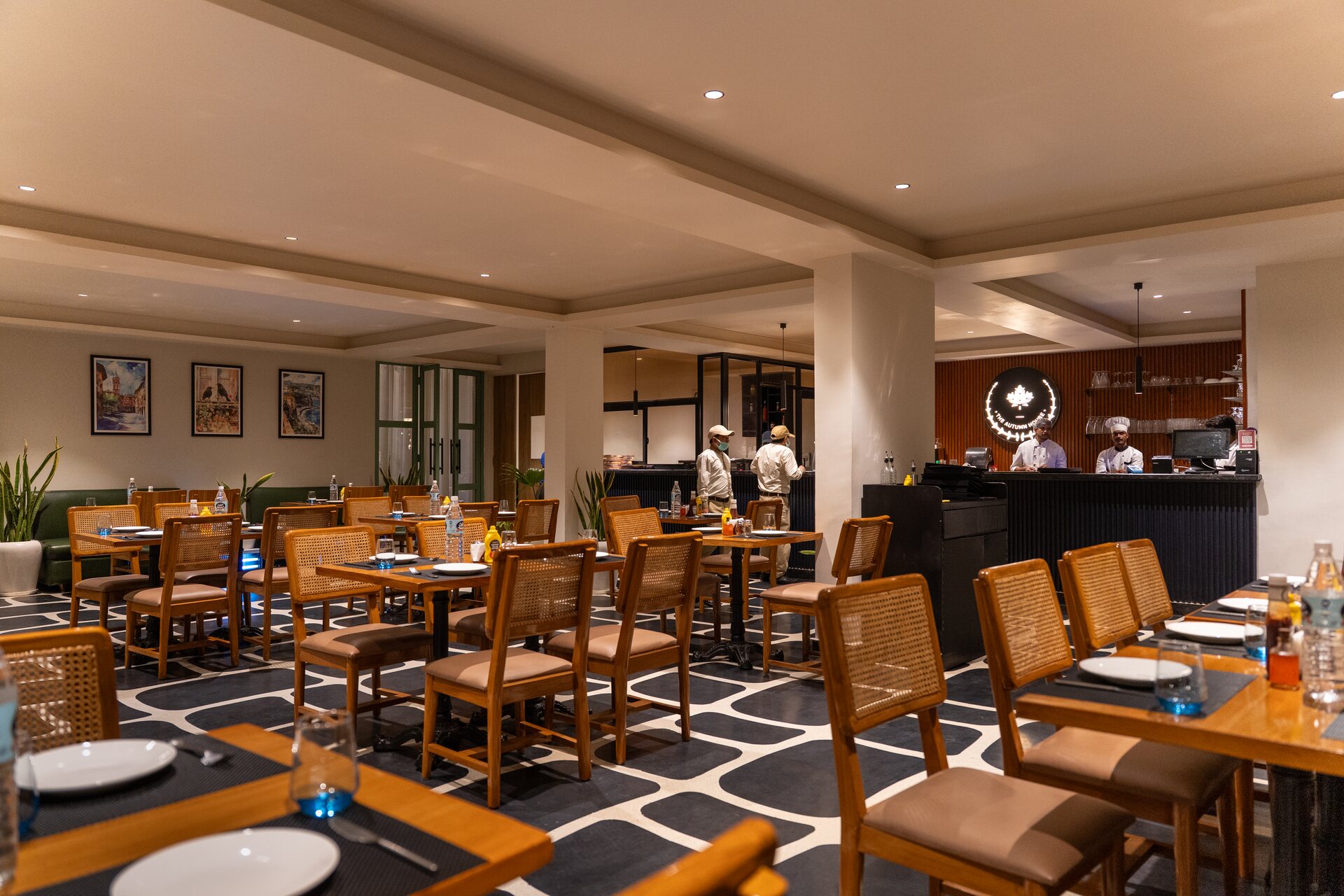 The Noida private dining space, cane chairs set at every table and the open kitchen at the back