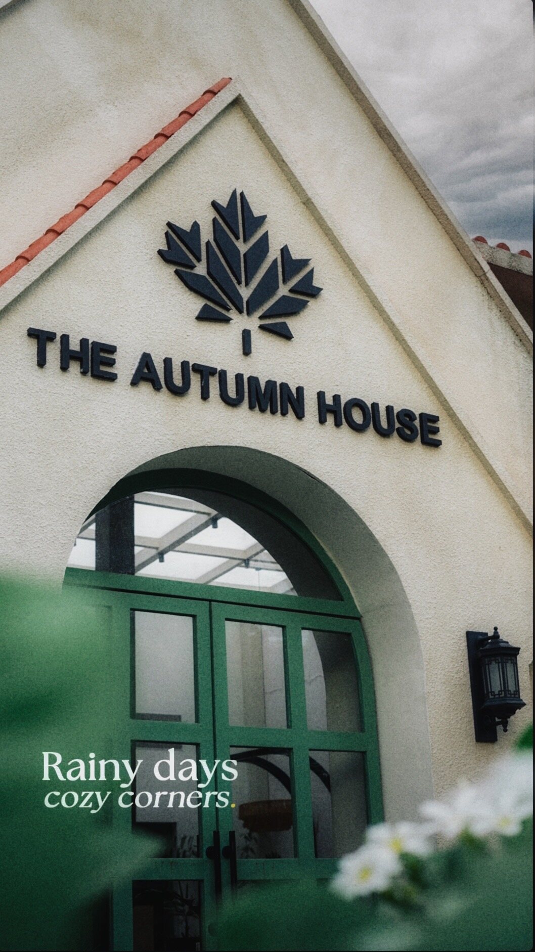 The white gabled front of the Noida house, its maple-leaf sign above a green arched door