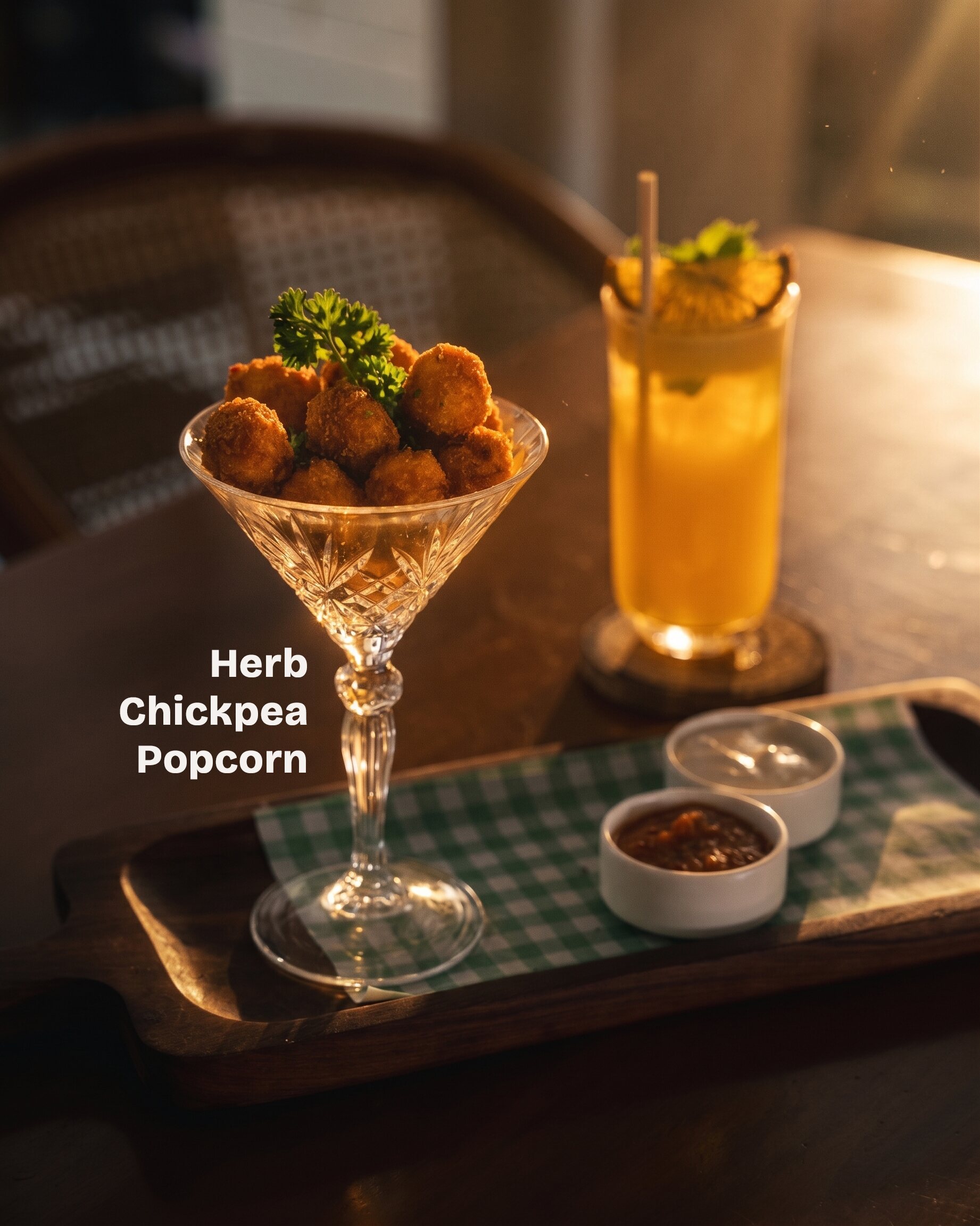 Herb chickpea popcorn in a coupe glass beside a golden cocktail